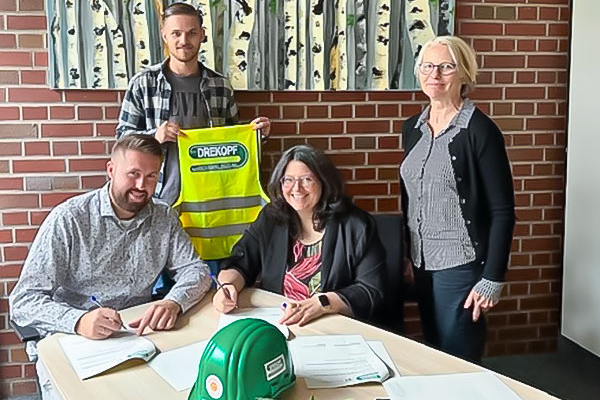 Vier Personen sitzen oder stehen gemeinsam am Tisch