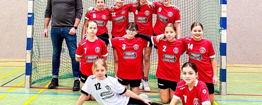 Handballteam Mädchen sitzt und steht mit Trainer im Tor