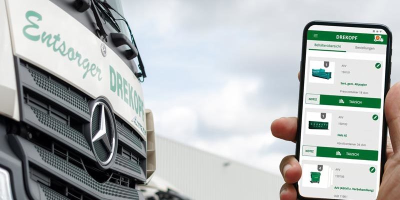 Eine Person hält ein Smartphone, auf dem eine App für die Abfallwirtschaft angezeigt wird, neben einen weißen Mercedes-Benz-Lkw mit der Aufschrift Entsorger DREIKOPF auf der Seite. Im Hintergrund sind Industriegebäude und ein bewölkter Himmel zu sehen.